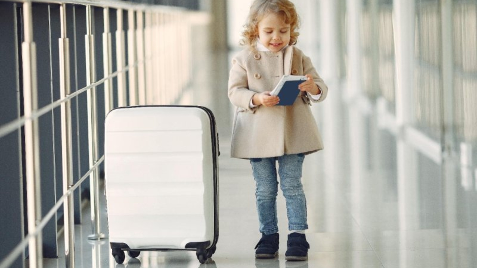 Niña con maleta y pasaporte en un aeropuerto antes de un viaje al extranjero