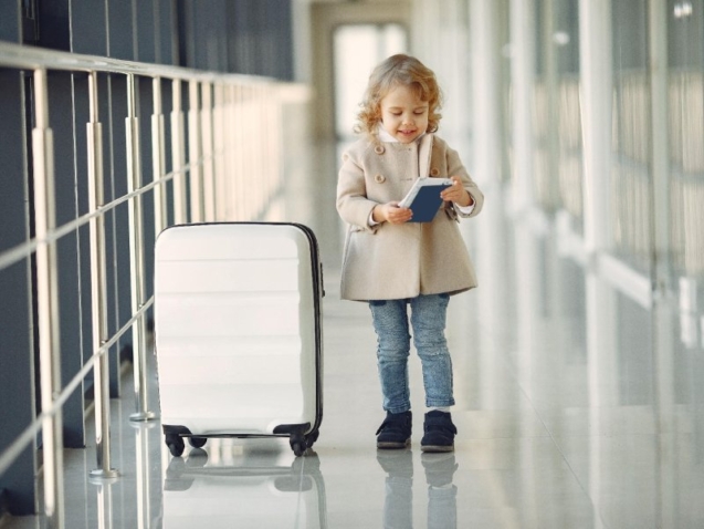 Niña con maleta y pasaporte en un aeropuerto antes de un viaje al extranjero