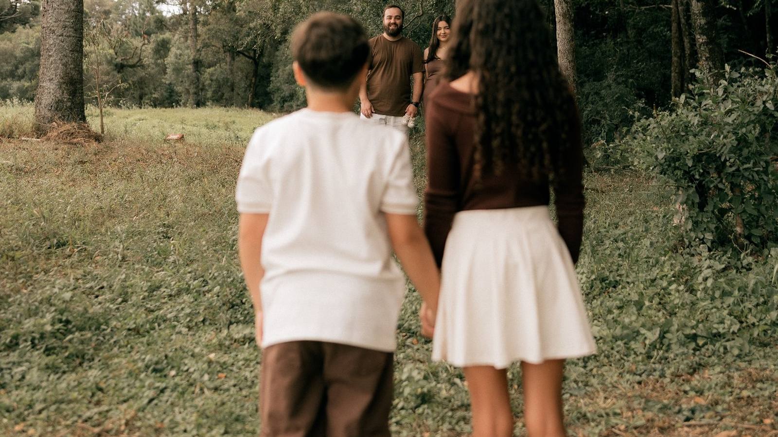 Dos hermanos de la mano mirando a sus padres: a qué edad puede un hijo decidir con quién vivir