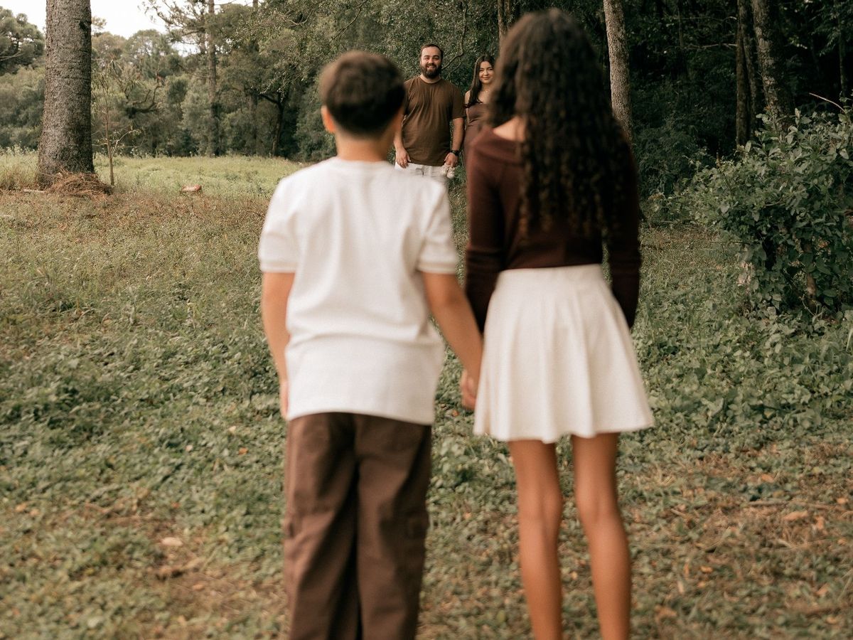 Dos hermanos de la mano mirando a sus padres: a qué edad puede un hijo decidir con quién vivir