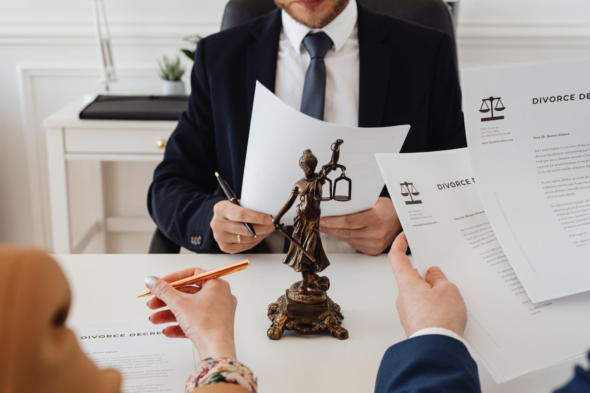 Profesionales legales revisando documentos de divorcio en una oficina de abogados con una estatua de la Justicia.